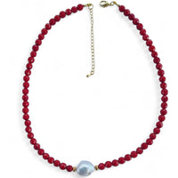 Necklace with red beads and a white keshi pearl on a white background