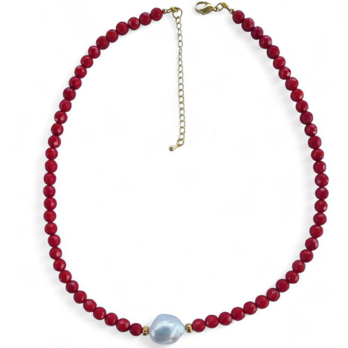 Necklace with red beads and a white keshi pearl on a white background