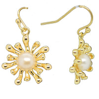 A pair of gold earrings featuring a freshwater pearl at the center with anemone arms extending out in a floral pattern.