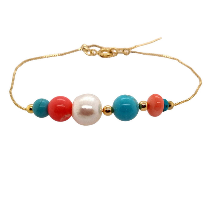 A bracelet with a combination of turquoise, freshwater pearls, and coral beads, strung together on a gold-colored metal chain.