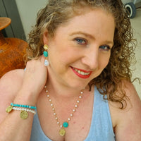 Woman wearing a blue tank top and jewelry, with a neutral background Turquoise and pearl jewellery