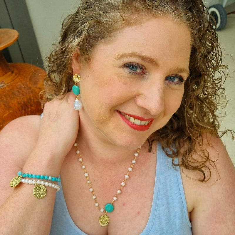 Woman wearing a blue tank top and jewelry, with a neutral background Turquoise and pearl jewellery